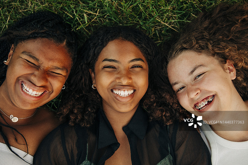 躺在草地上欢笑的快乐青少年女孩肖像图片素材