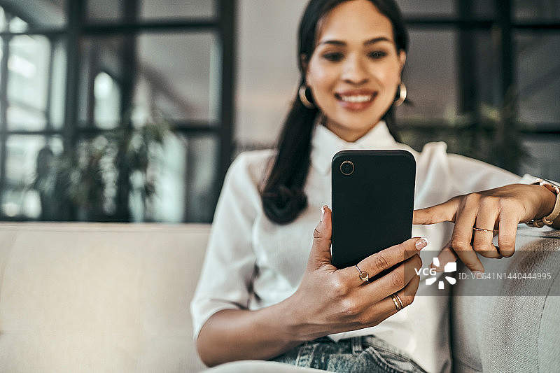 职场女性在办公室沙发上使用手机进行社交媒体互动和求职图片素材