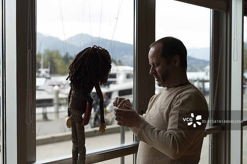 经验丰富的傀儡师在窗前操纵木偶图片素材