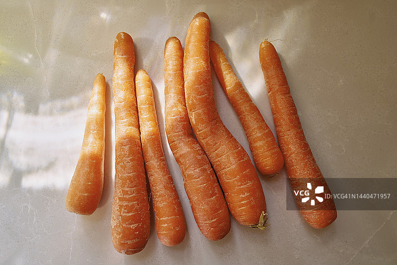 阳光明媚的米色背景上的橙色胡萝卜静物俯视图图片素材