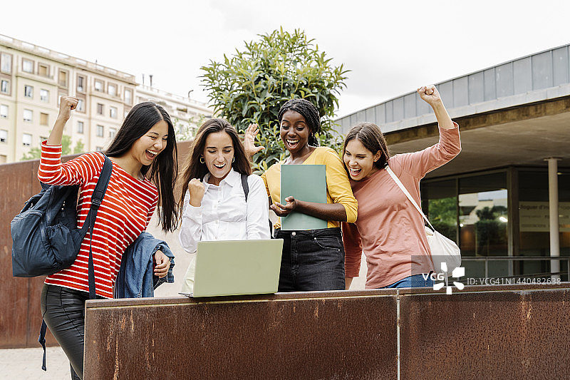 女学生看笔记本电脑，举手庆祝图片素材