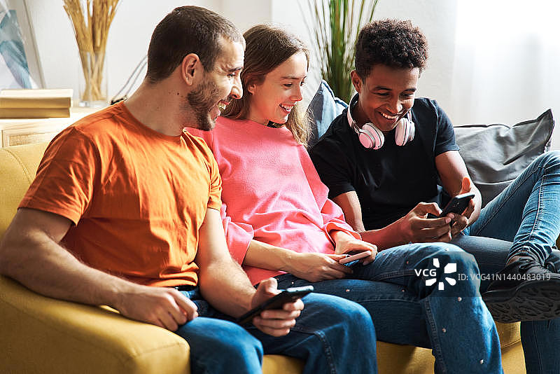 年轻男人在家中客厅用手机向朋友们展示女儿的照片，与朋友们分享图片素材