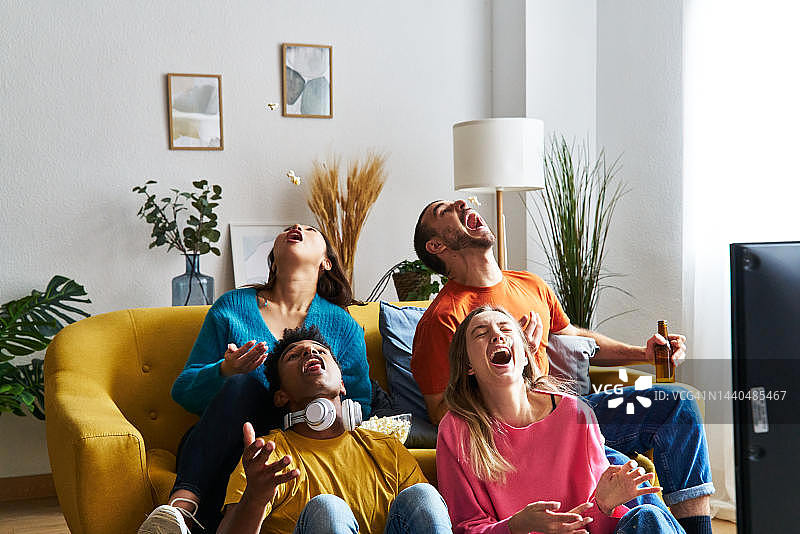 朋友们在家中客厅看电视欢笑图片素材