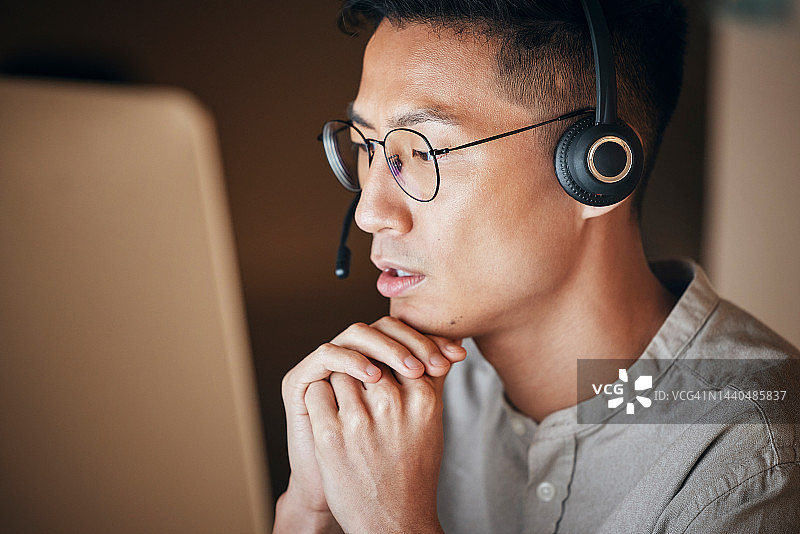 呼叫中心：亚洲男人在电脑前使用CRM在线解决问题，客户服务和专业电话销售员工在办公室工作到深夜图片素材