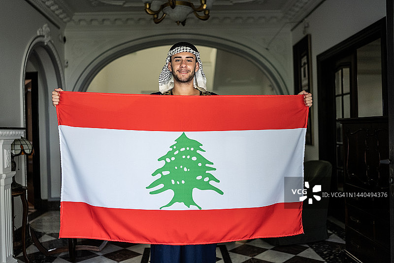 在家手持黎巴嫩国旗的年轻男子肖像图片素材
