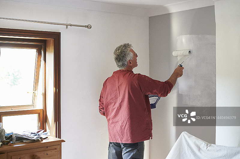 一位年长的男人正在装饰他的卧室图片素材
