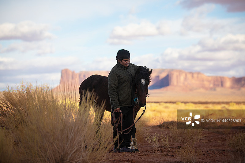 纪念碑谷中骑马的纳瓦霍男孩图片素材