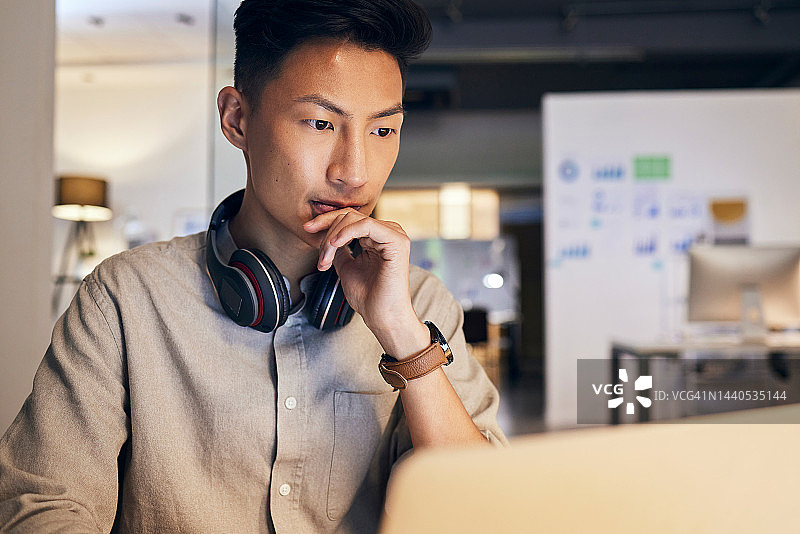 思考，办公室里的笔记本电脑和IT商务人士，用于网站设计、软件开发或市场调研，戴着耳机。信息技术，电脑和亚洲男性进行数字分析图片素材