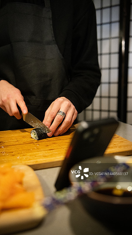 青年男人在家做寿司看手机图片素材