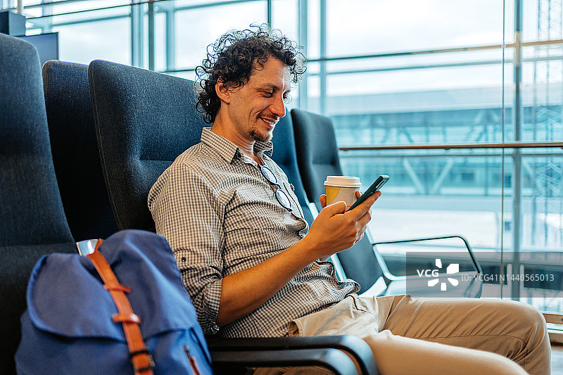 在斯德哥尔摩机场使用智能手机喝咖啡的年轻人图片素材