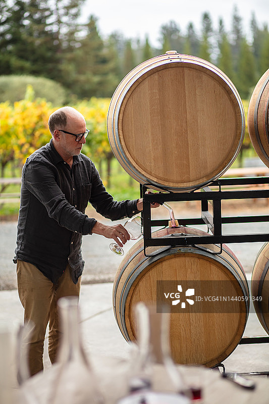 酿酒师用移液管从桶中提取葡萄酒进行品尝图片素材