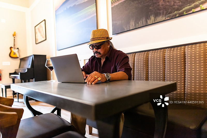 在酒吧使用笔记本电脑的年长男人图片素材