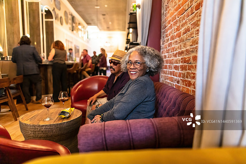 在热闹的酒吧里对着镜头微笑的女人图片素材