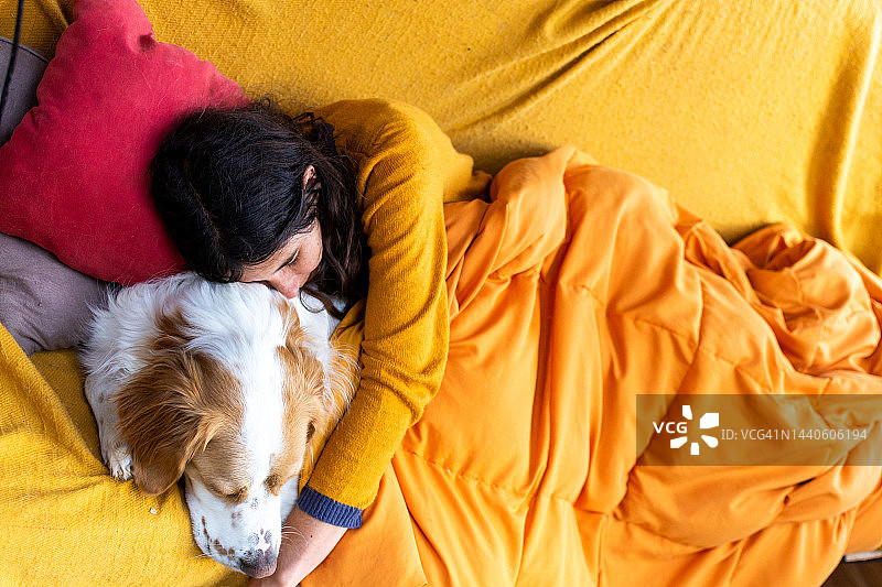 年轻女人抱着她的狗睡觉，爱图片素材