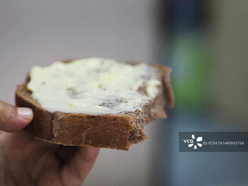 手持黄油巧克力炼乳面包图片素材