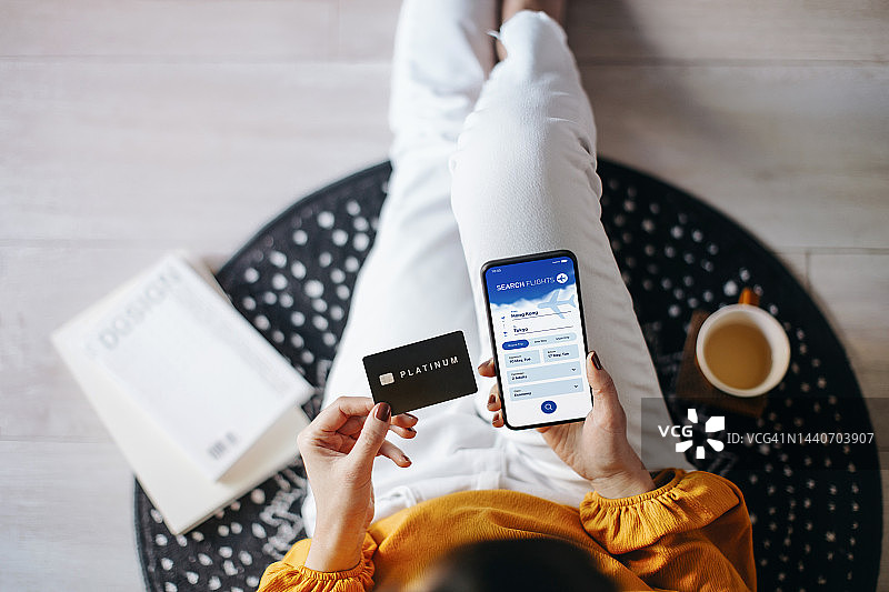 亚洲年轻女性在家用手机在航空公司网站上预订机票，并用信用卡付款图片素材