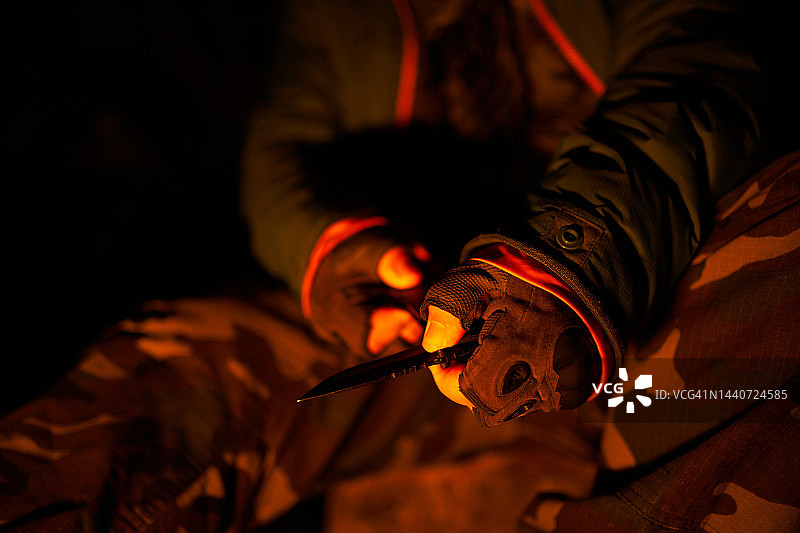男子在篝火旁手持美工刀素材照片图片素材