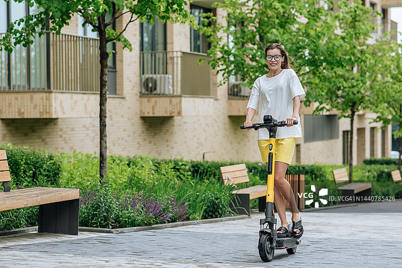 快乐的年轻女子骑着电动滑板车图片素材