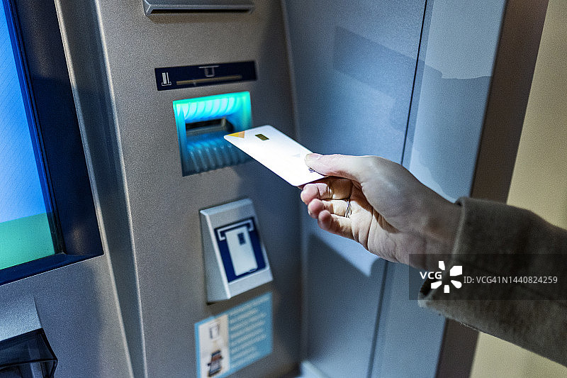 在城市街道上用ATM机的年轻女性图片素材
