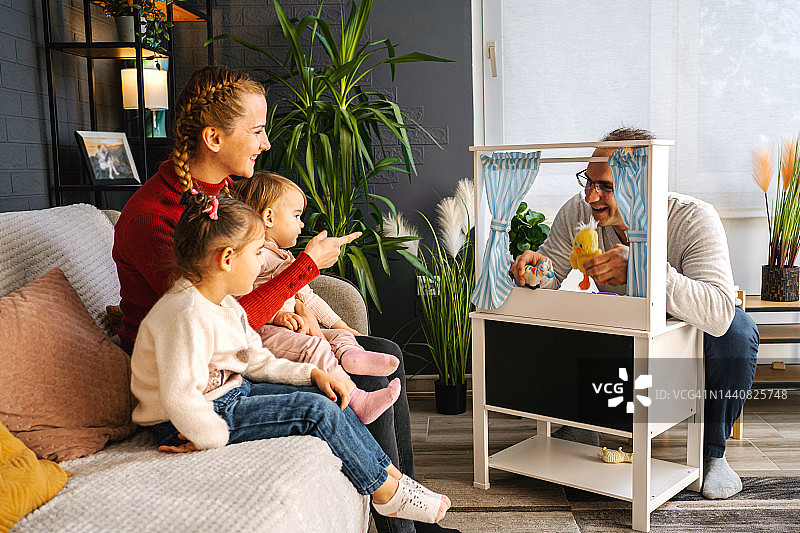 慈爱的父亲在家为女儿们表演木偶戏图片素材