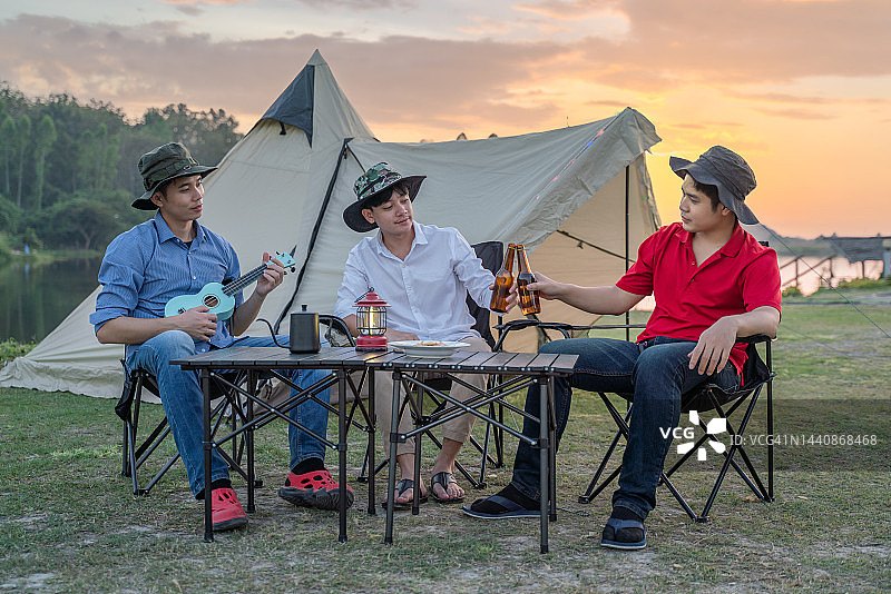 露营者在湖边黄昏日落时弹吉他图片素材