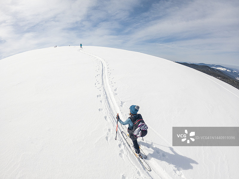 女子滑雪者在美丽的冬季景色中登上山顶图片素材