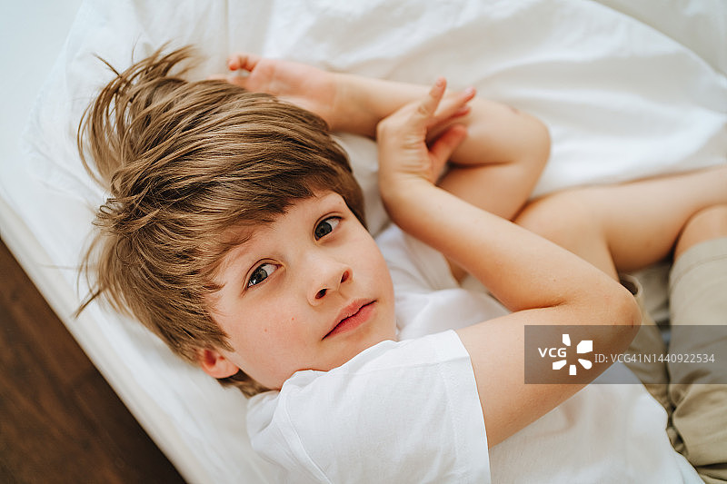 孤儿与寄养家庭：躺在床上的可爱男孩看着镜头图片素材