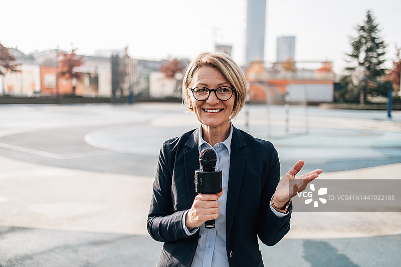 女记者在城市街道进行现场直播图片素材