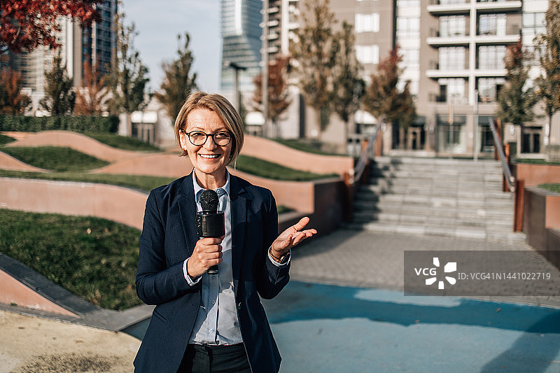 女记者在城市街道进行现场直播图片素材