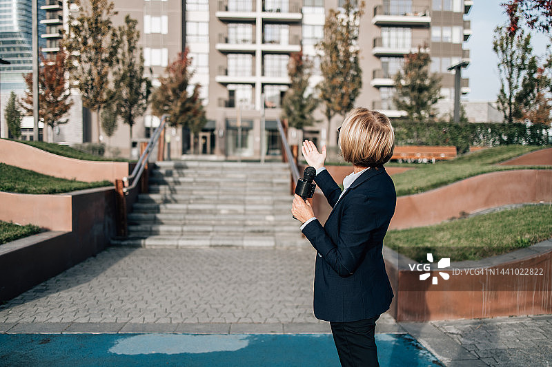 女记者在城市街道进行现场直播图片素材