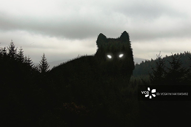 巨狼在冬季森林上方的剪影，眼睛发出光芒图片素材