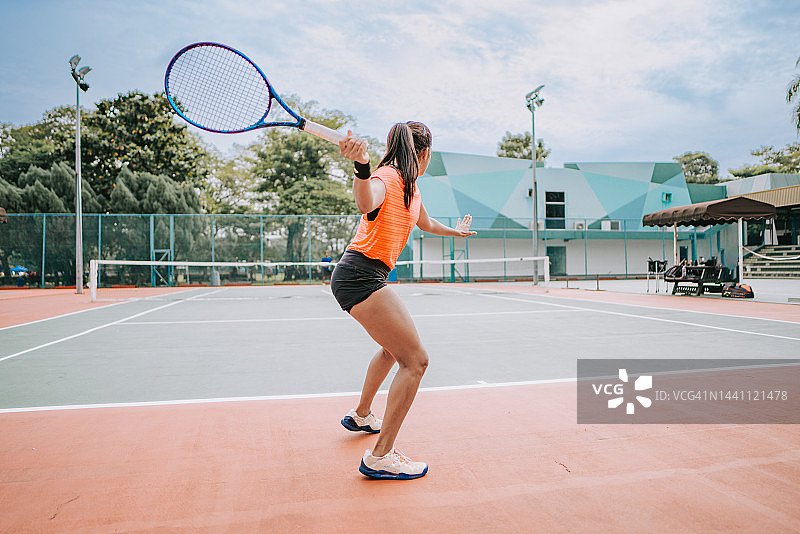 亚洲印度女网球运动员在教练的指导下在网球场练习发球图片素材