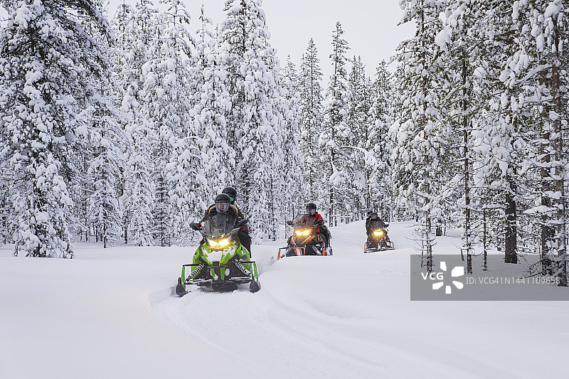 游客在白雪皑皑的森林里骑雪地摩托图片素材