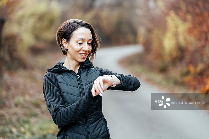 运动型年轻女子在慢跑后查看智能手表上的时间图片素材