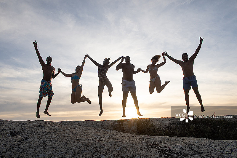 剪影：六个朋友手牵手跳跃图片素材
