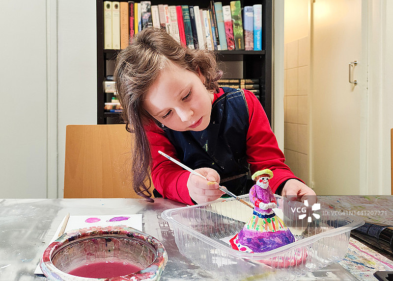 7岁的白人女孩正在给小雕像涂色图片素材