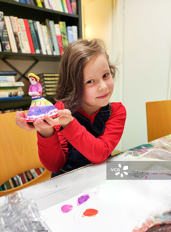 7岁的白人女孩制作并彩绘泥塑，儿童创意作品图片素材