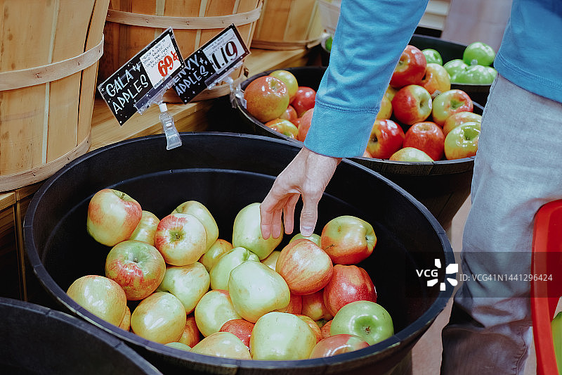 男子在购物时伸手去拿苹果图片素材