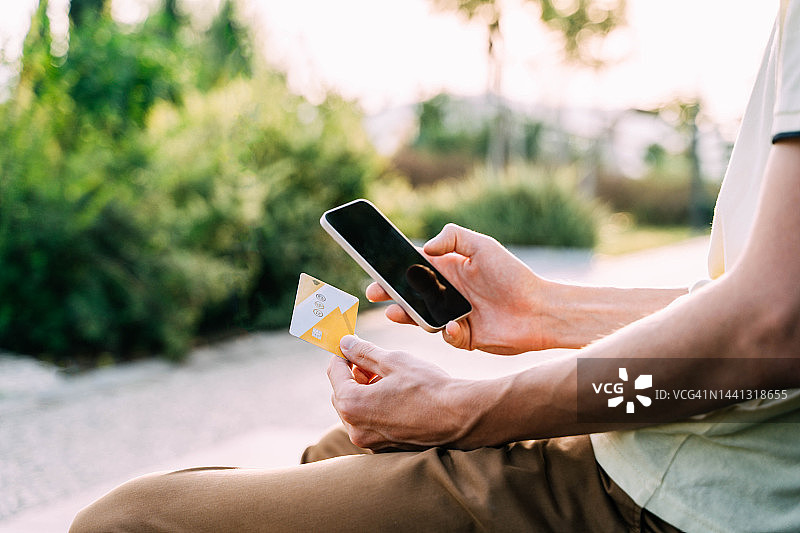 男人手中的智能手机和信用卡图片素材