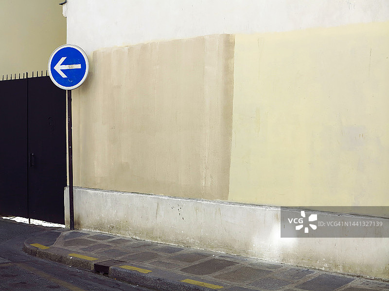 巴黎的彩绘风化混凝土墙与黑色金属门、街道和路标图片素材