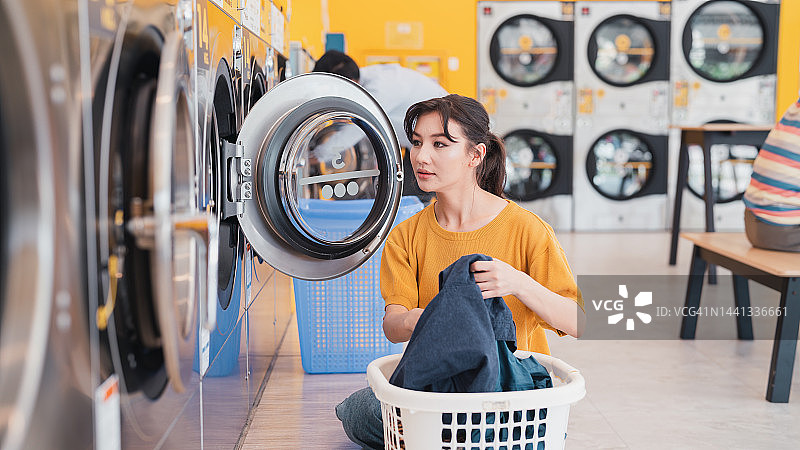在自助洗衣店使用洗衣机的女人图片素材