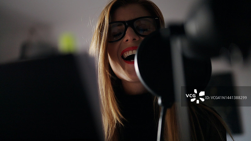 年轻白人女性在家庭录音室对着麦克风唱歌特写镜头图片素材