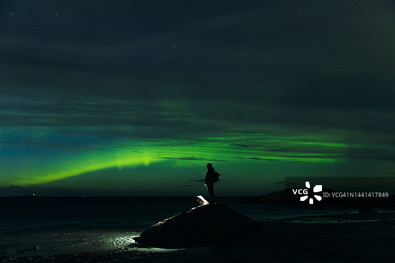 带着狗欣赏挪威北极光奇观的女人图片素材