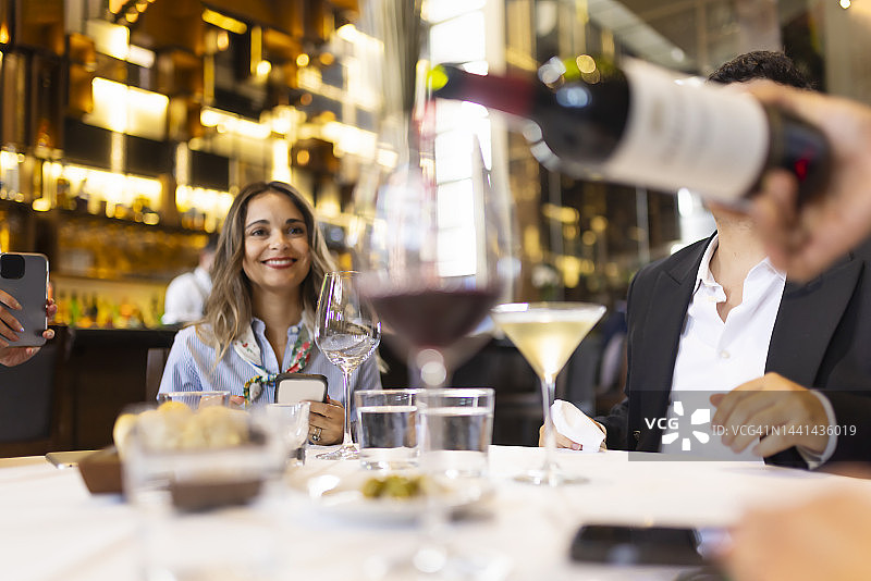 商务会议中手持葡萄酒的微笑女人图片素材