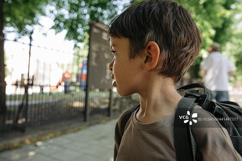沉思的男孩背着书包望向远方图片素材