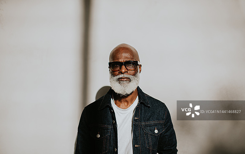 一个自信的老绅士的肖像直视相机在一个普通的背景图片素材