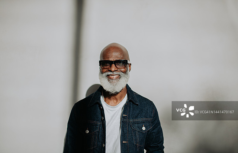 一个自信的老绅士的肖像直视相机在一个普通的背景图片素材