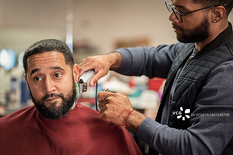 在黑人理发店里，黑人顾客正在理发图片素材