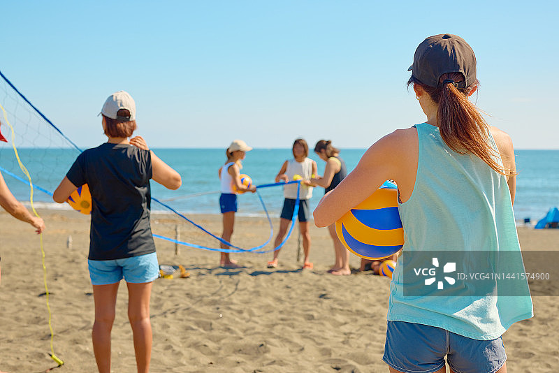 妇女在海滩上设置排球场地图片素材
