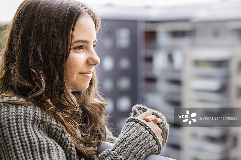 微笑的少女在阳台上欣赏风景图片素材